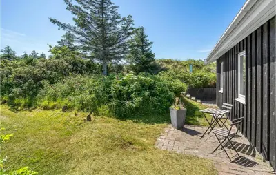 a patio with a table and chairs next to a house at Holiday Home Lyngvej Blokhus Iv in Blokhus