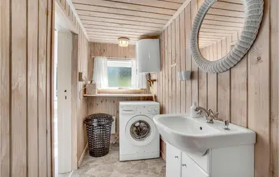 a bathroom with a washing machine and a sink at Holiday Home Lyngvej Blokhus Iv in Blokhus