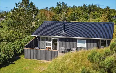a small house on a hill with two chairs at Holiday Home Kristinesvej Blokhus X in Blokhus