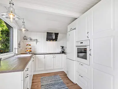 a white kitchen with white cabinets and a window at 6 person holiday home in Vinderup-By Traum in Vinderup