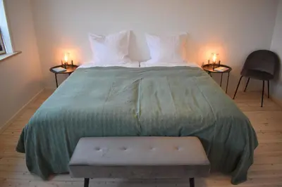 a large bed with a green blanket and two chairs at Viking Surf House in Klitmøller