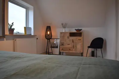 a bedroom with a bed and a dresser and a window at Viking Surf House in Klitmøller