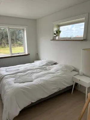 a white bedroom with a bed and two windows at Viking Surf House in Klitmøller