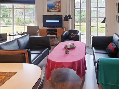 a living room with a red table with chairs and a television at 8 person holiday home in Løgstør-By Traum in Løgsted