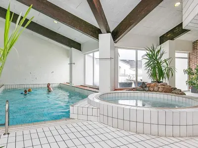 a large swimming pool with two people swimming in it at 6 person holiday home in Brovst-By Traum in Brovst