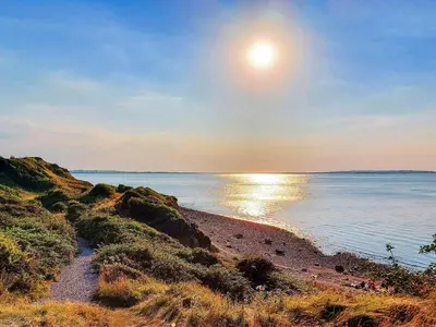 a beach with the sun setting over the water at 6 person holiday home in Løgstør-By Traum in Løgsted