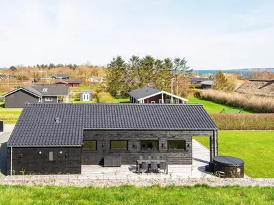 a house with a black roof on a field at 6 person holiday home in Lemvig-By Traum in Lemvig