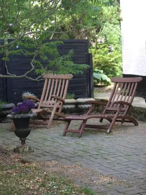two wooden chairs sitting next to a vase with flowers at Fadeburet på Skibstedgaard in Tvolm