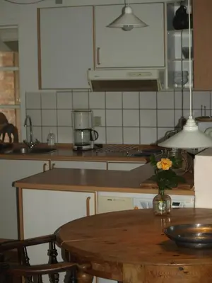 a kitchen with a table with a vase of flowers on it at Fadeburet på Skibstedgaard in Tvolm
