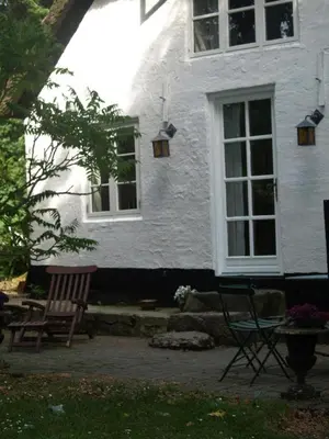 a white house with two chairs in front of it at Fadeburet på Skibstedgaard in Tvolm