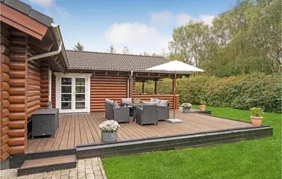 a wooden deck with chairs and an umbrella at Holiday Home Ramshule Farsø Xii in Farsø