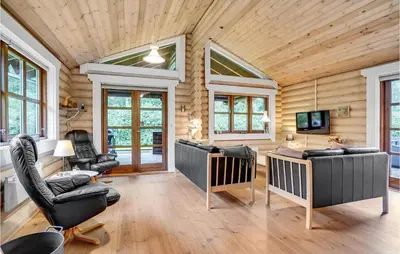 a living room with chairs and a television in a log cabin at Holiday Home Ramshule Farsø Xii in Farsø