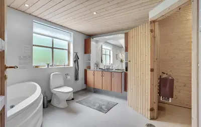 a bathroom with a tub and a toilet and a sink at Holiday Home Benediktesvej Løgstør X in Løgstør