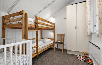 a bedroom with two bunk beds and a chair at Holiday Home Kjeldhøj Farsø Xi in Farsø