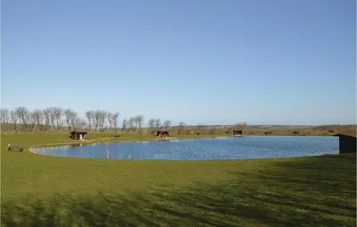 a large pond with two cows standing in the grass at Amazing Home In Løgstør With Kitchen in Løgstør
