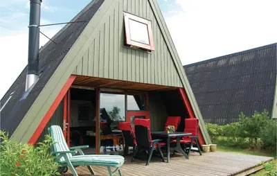 a barn house with a table and chairs on a deck at Holiday Home Golfsvinget in Farsø