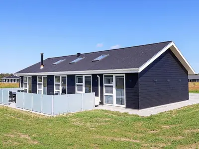 a black house with a lot of windows at 10 person holiday home in Løkken-By Traum in Løkken
