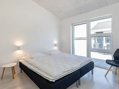 a white bedroom with a large bed and a window at 10 person holiday home in Løkken-By Traum in Løkken