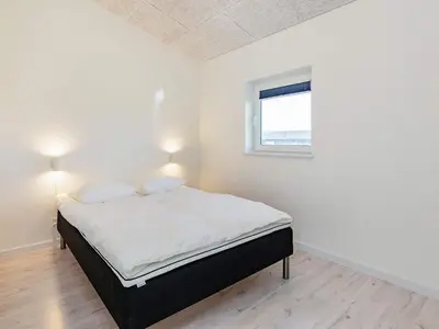 a bedroom with a bed with white sheets and a window at 10 person holiday home in Løkken-By Traum in Løkken