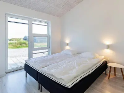 a large bed in a room with a large window at 10 person holiday home in Løkken-By Traum in Løkken