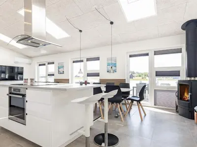 a kitchen with white cabinets and a table and chairs at 10 person holiday home in Løkken-By Traum in Løkken