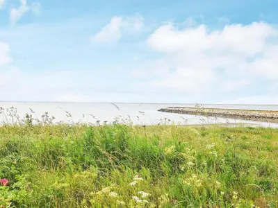 a grassy field with the ocean in the background at 10 person holiday home in Vestervig-By Traum in Vestervig