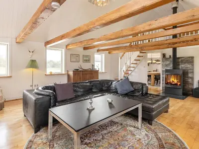 a living room with a black leather couch and a table at 12 person holiday home in Thisted-By Traum in Thisted