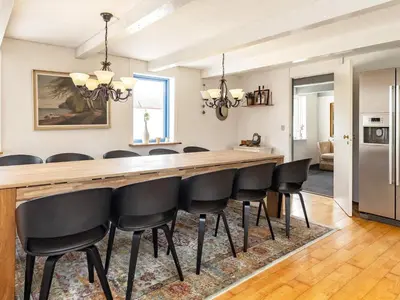 a kitchen and dining room with a long bar with black chairs at 12 person holiday home in Thisted-By Traum in Thisted