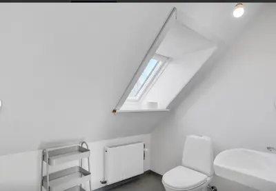 a white bathroom with a toilet and a window at Lundø in Højslev