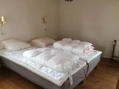 two unmade beds in a room with white sheets and pillows at Lundø in Højslev