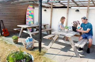a man and a woman sitting at a picnic table with a laptop at Stone Mountain BnB in Stenbjerg