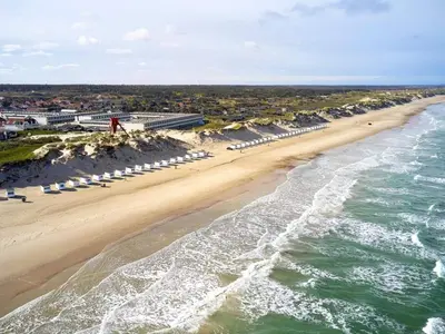 an aerial view of a beach with umbrellas and the ocean at 4 person apartment in holiday park Blokhus in Blokhus