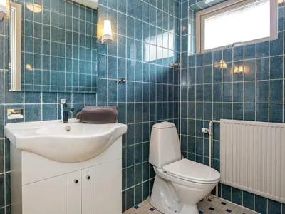 a blue tiled bathroom with a toilet and a sink at 8 person holiday home in Struer-By Traum in Struer