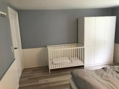 a bedroom with a crib and a white cabinet at Sommerhus på Mors in Øster Assels