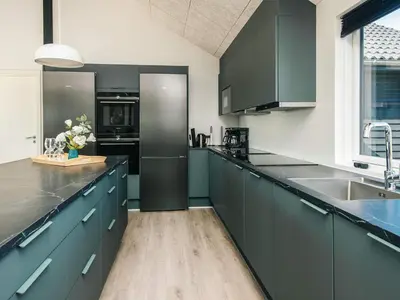 a kitchen with dark green cabinets and a refrigerator at Luxury Retreat with Pool - By Traum Ferienwohnungen in Harboør