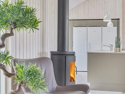 a fireplace in a kitchen with a chair and plants at Luxury Retreat by Limfjorden - By Traum Ferienwohnungen in Spottrup