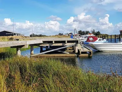 a boat is docked next to a wooden dock at 6 person holiday home in Vestervig-By Traum in Vestervig