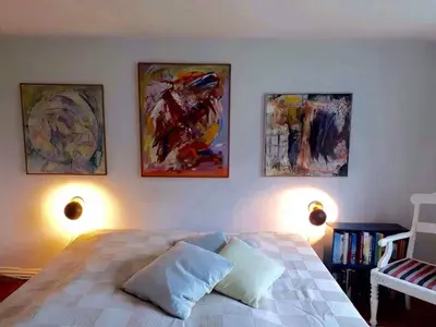 a bedroom with a bed with three paintings on the wall at Glædegården -Glaede Landhof- 12 beds! in Frøstrup