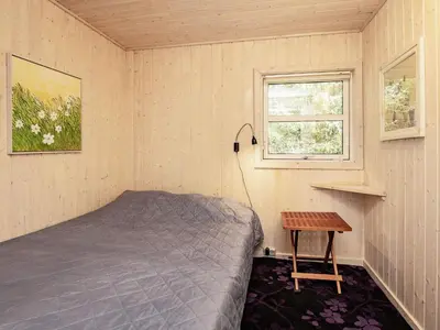 a bedroom with a bed and a table and a window at 8 person holiday home in Blokhus-By Traum in Blokhus