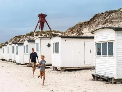 a man and a boy running on the beach at 8 person holiday home in Blokhus-By Traum in Blokhus