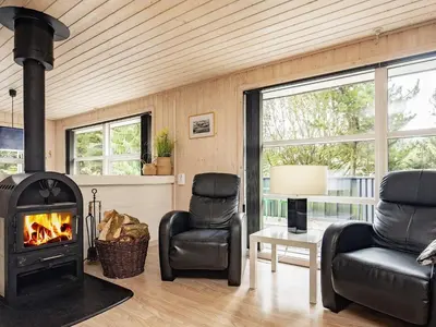 a living room with a fireplace and two chairs at 8 person holiday home in Blokhus-By Traum in Blokhus