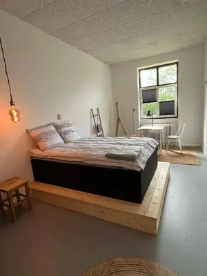 a bedroom with a large bed on a wooden platform at Room 3 - Hawkraft kulturhotel in Vestervig