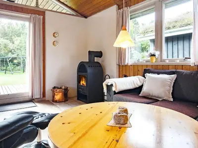 a living room with a wooden table and a wood stove at Cozy Cottage near Blokhus - By Traum Ferienwohnungen in Blokhus