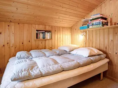 a large bed in a room with wooden walls at Cozy Cottage near Blokhus - By Traum Ferienwohnungen in Blokhus