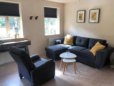 a living room with a blue couch and a table at Istrup gammel skole in Bedsted Thy