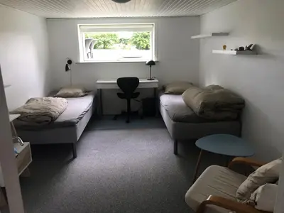 a room with two beds and a desk and a window at Ny Roesgaard in Lemvig
