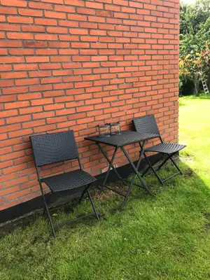 two chairs and a table next to a brick wall at Ny Roesgaard in Lemvig