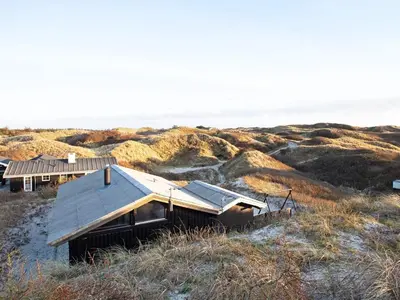 an old house on a hill with the ocean in the background at 6 person holiday home in Saltum-By Traum in Saltum