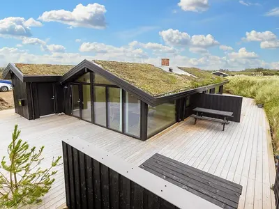a black house with a grass roof on a deck at 6 person holiday home in Saltum-By Traum in Saltum