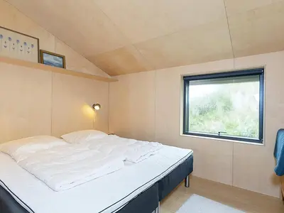 a large bed in a small room with a window at 6 person holiday home in Saltum-By Traum in Saltum